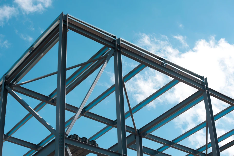 Ouvrier en équipement de protection individuelle effectuant des travaux de soudage sur structure métallique d'un bâtiment industriel en construction