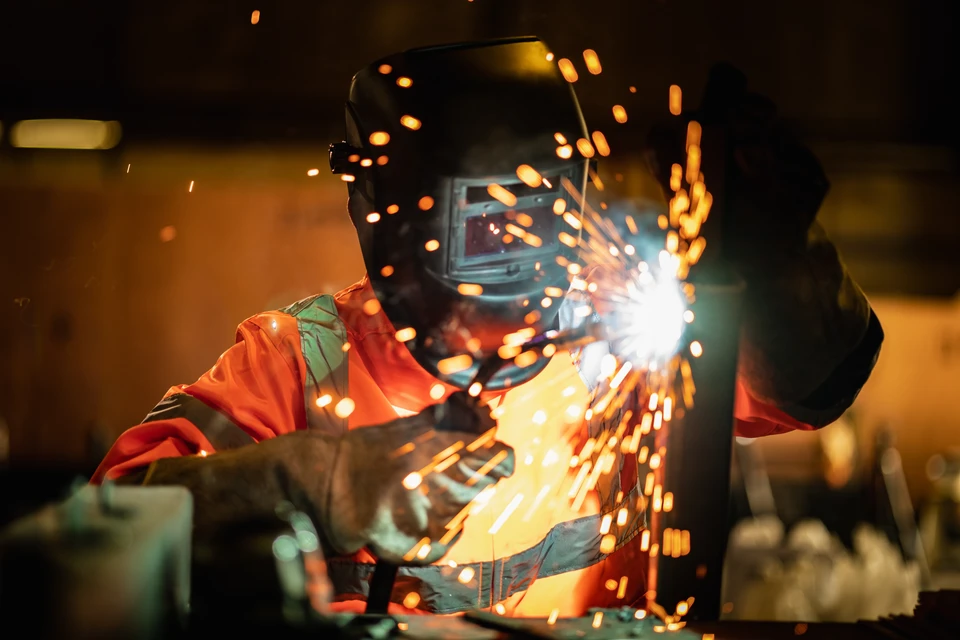 Ouvrier en équipement de protection individuelle utilisant une cisaille à tôle pneumatique pour découper une plaque métallique galvanisée